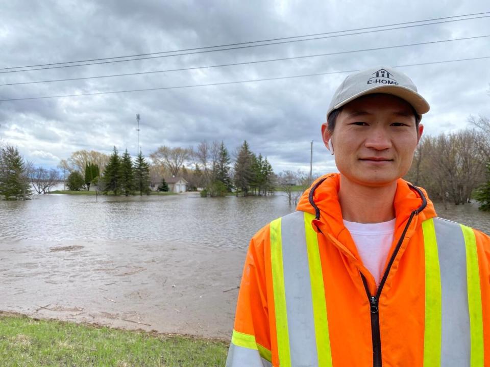 Chao Shen is pictured in front of rising floodwaters around his home in the St. Adolphe, Man., area. (Karen Pauls/CBC - image credit)