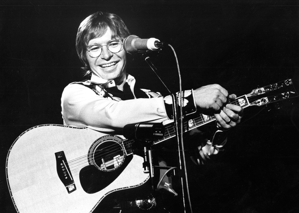 John Denver performs onstage.