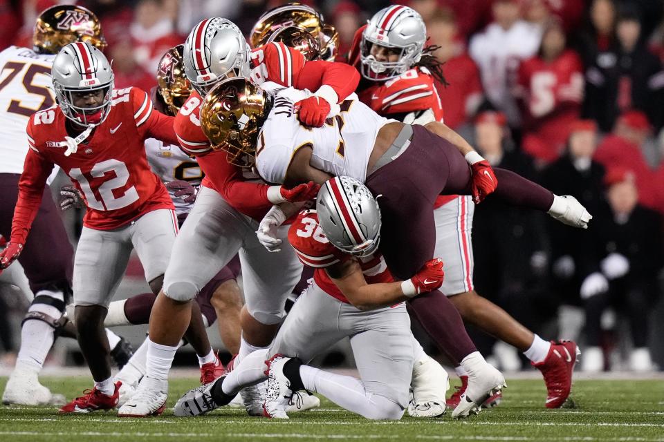 Ohio State defensive tackle hero Kanu (93) and linebacker Gabe Powers (36) tackle Minnesota running back Jordan Nubin during the Buckeyes 37-3 win Saturday.