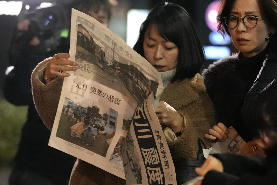 People read extra edition of Yomiuri Shimbun newspaper reporting the earthquakes Monday, Jan. 1, 2024 in Tokyo. Japan issued tsunami alerts and ordered evacuations following a series of earthquakes on Monday that started a fire and trapped people under rubble on the west coast of its main island.(AP Photo/Shuji Kajiyama)