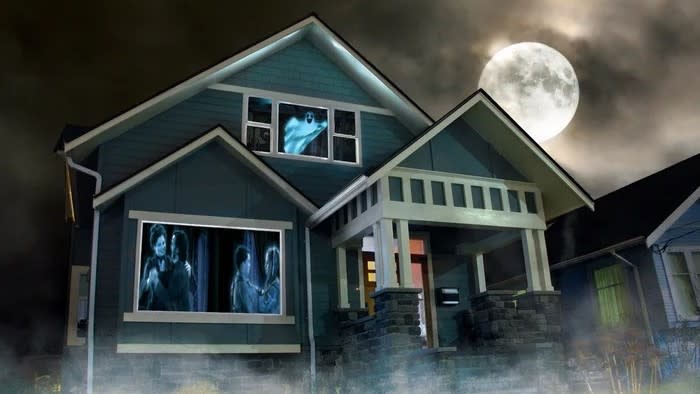  Halloween house exterior with scary images projected on window. 