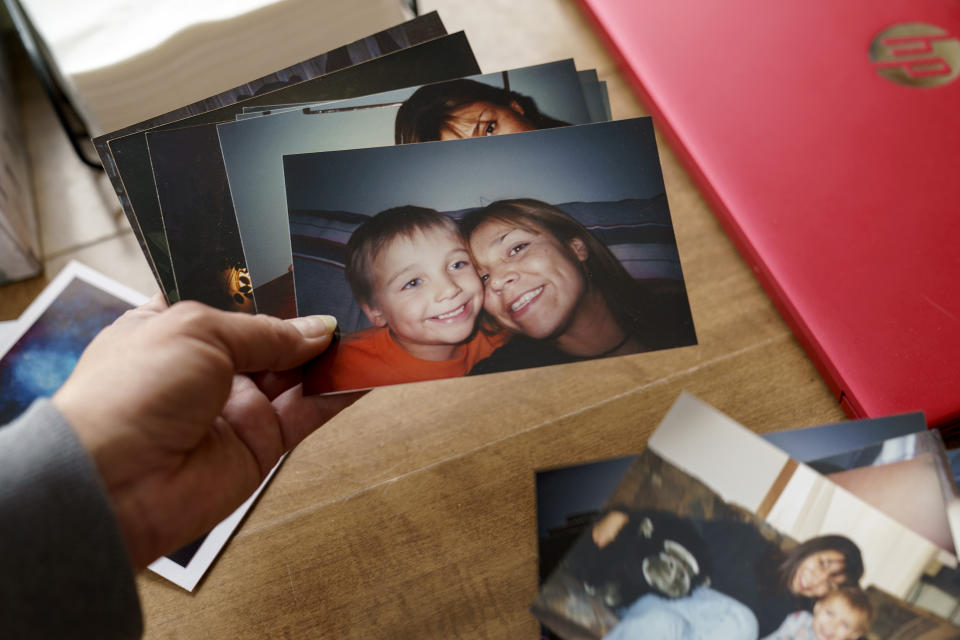 Rachel Taylor looks through old photos of her with her son, Kyle Domrese, as a young boy, Wednesday, Nov. 17, 2021, in the home they shared in Bemidji, Minn. When he was born, the nurse put him on her chest, and he'd looked at her with such intensity. His eyes were always like that, like a cat's, she thinks. He loved animals. She kept everything he ever made her, birthday cards, childhood pottery. "You're the best mom in the world," he'd write, and she loved it because she'd always felt like a bad one. (AP Photo/David Goldman)