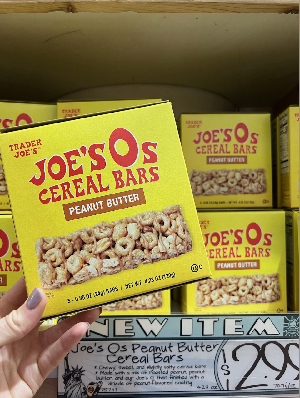 Hand holding a box of Joe's O's Peanut Butter Cereal Bars at a store with price tag shown