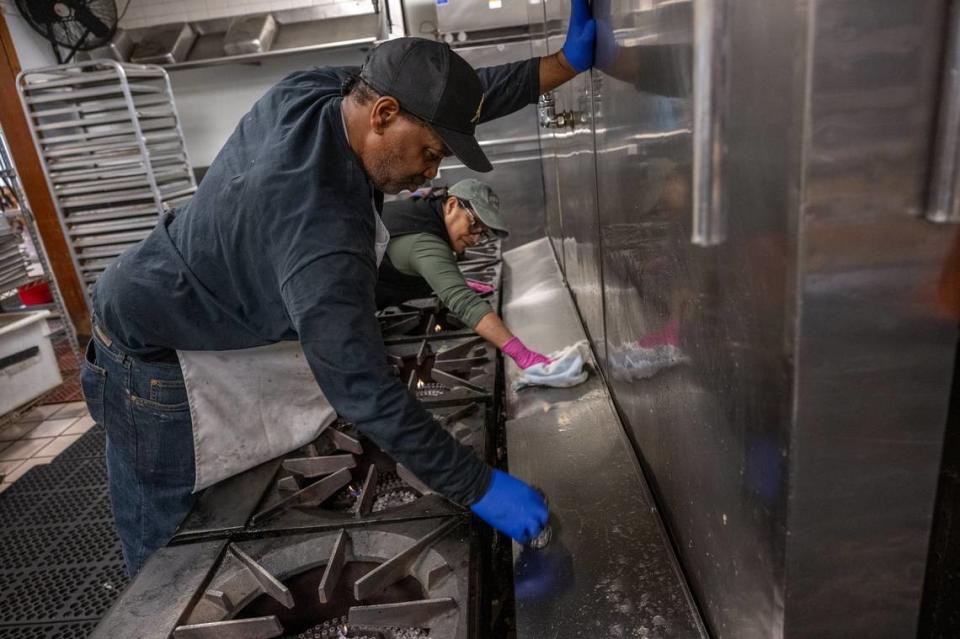 Chef Edwin Burton of Loaves & Fishes helps clean stoves with volunteer Ja’net Blea last week. Six of their commercial single-burner gas stoves are at least 25 years old and frequently sputter out and need repair.