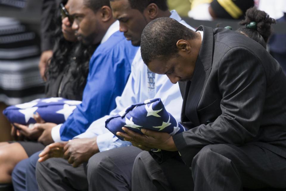 Decondi Mayo, father of U.S. Navy Petty Officer 2nd Class Mark Mayo, of Hagerstown, Md., bows his head as he holds a flag during a burial service at Arlington National Cemetery in Arlington, Va., Friday, April 25, 2014. Mayo was killed aboard the USS Mahan at Naval Station Norfolk, Va., after he dove in front of another sailor to protect her from a civilian truck driver who had seized her gun. Mayo was awarded the Navy Marine Corps Medal, the highest non-combatant decoration for heroism by a sailor or Marine. (AP Photo/ Evan Vucci)