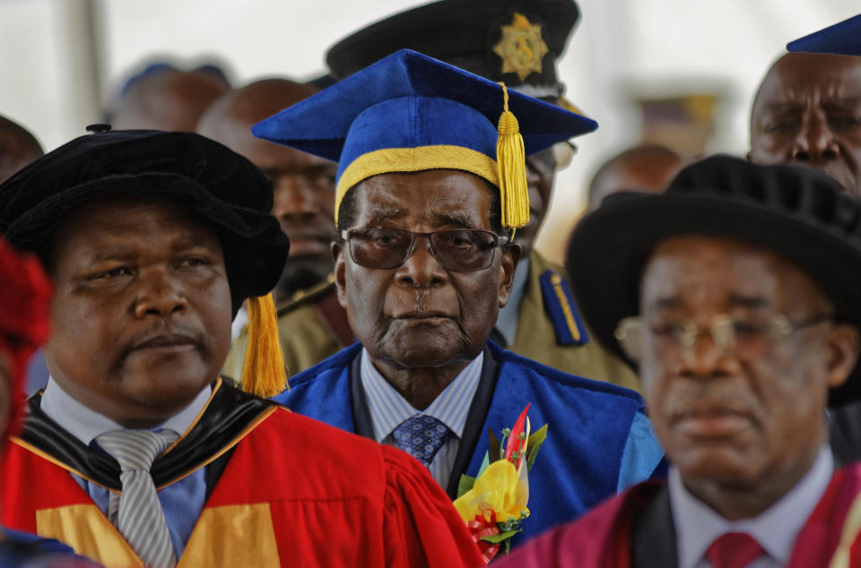 FILE - In this Friday, Nov. 17, 2017 file photo Zimbabwe's President Robert Mugabe, center, arrives to preside over a student graduation ceremony at Zimbabwe Open University on the outskirts of Harare, Zimbabwe. On Friday, Sept. 6, 2019, Zimbabwe President Emmerson Mnangagwa said his predecessor Robert Mugabe, age 95, has died. (AP Photo/Ben Curtis, File)