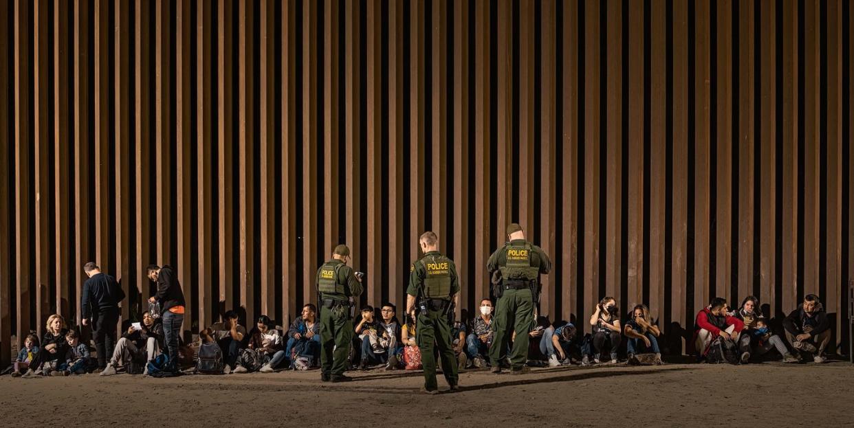 yuma, arizona june 21 us border patrol agents keep watch as immigrants wait to be processed by the us border patrol after crossing the border from mexico, with the us mexico border barrier in the background, at midnight on june 21, 2022 in yuma, arizona photo by qian weizhongvcg via getty images