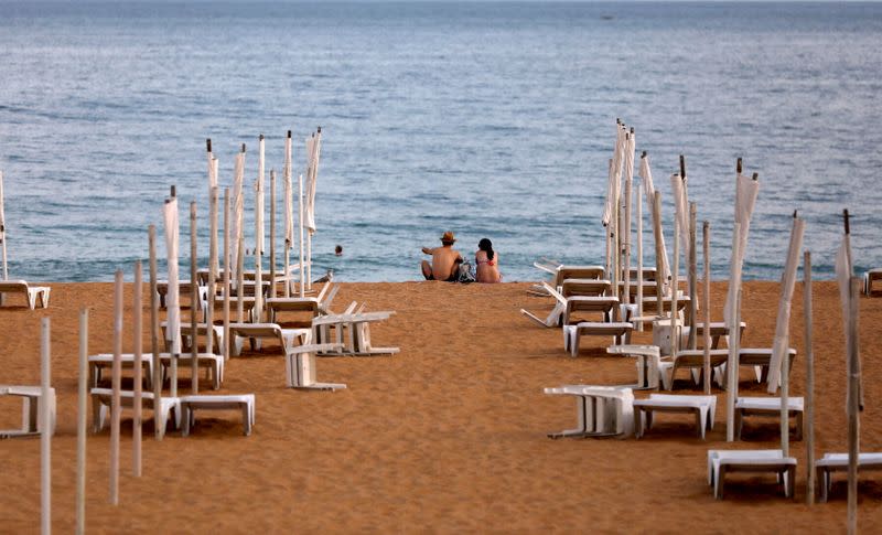 FILE PHOTO: A couple is seen next to rows of empty hammocks during the coronavirus pandemic in Albufeira, Portugal