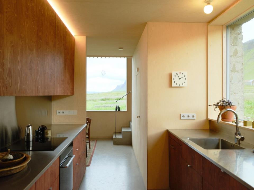 Kitchen space inside the Studio Bua-renovated Icelandic barn, with plenty of natural light and plywood paneling to keep the space feeling bright. 