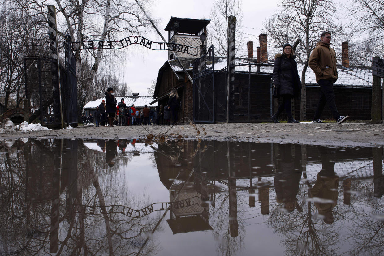 People walk next to the ''Arbeit Macht Frei" (Work Sets You Free) gate at the former Nazi German concentration and extermination camp Auschwitz-Birkenau in Oswiecim, Poland, Thursday, Jan. 26, 2023. Survivors of Auschwitz-Birkenau are gathering to commemorate the 78th anniversary of the liberation of the Nazi German death camp in the final months of World War II, amid horror that yet another war has shattered the peace in Europe. The camp was liberated by Soviet troops on Jan. 27, 1945. (AP Photo/Michal Dyjuk)