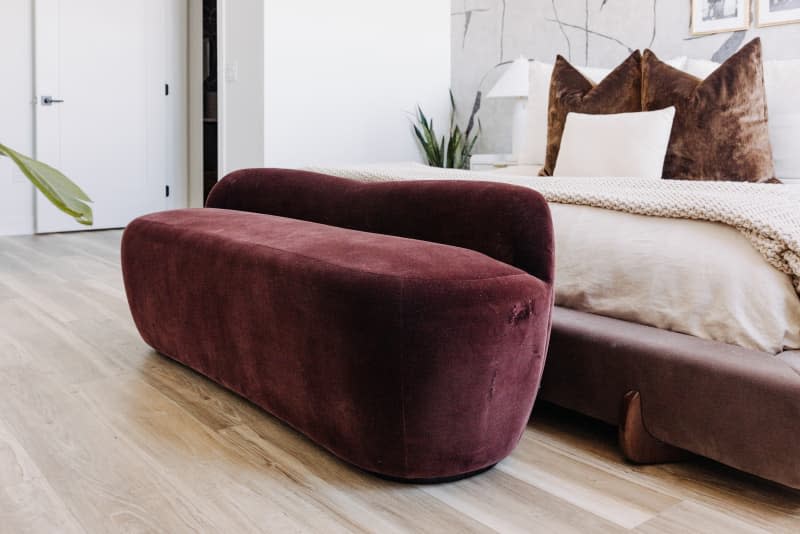 detail of wine-colored velvet bench in white bedroom