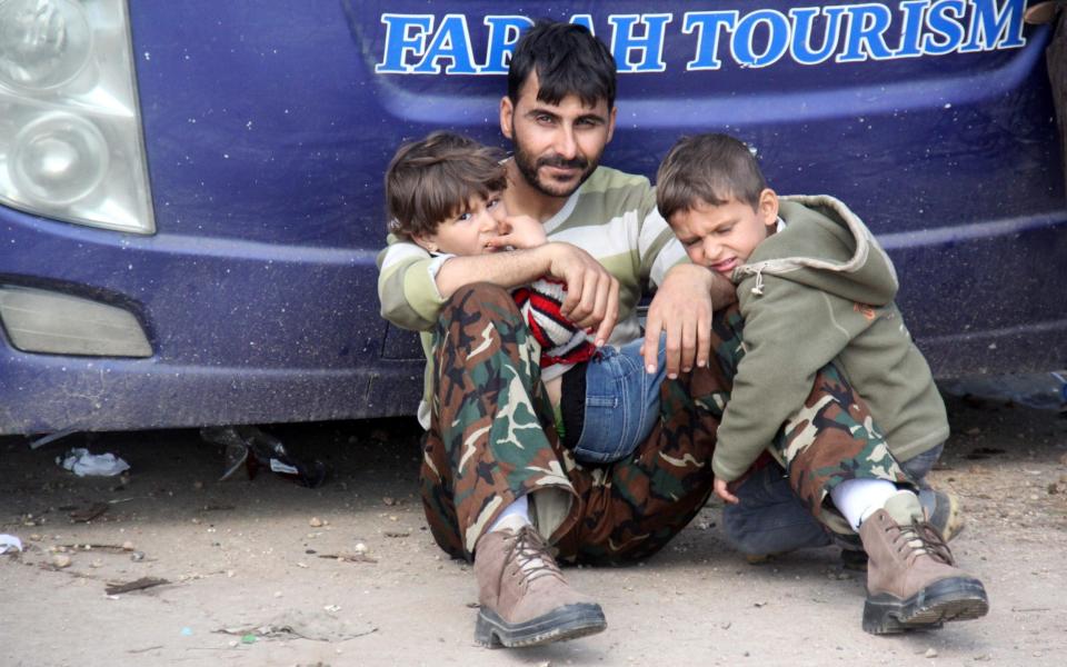 A Syrian man and his children who arrived a day earlier from government-held villages of Fuaa and Kafraya wait in rebel-held Rashidin, west of Aleppo city, following delays in evacuating them as the hard-won evacuation deal ran into trouble on April 15, 2017.  - Credit: AFP