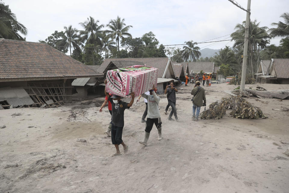 Villagers carry their belonging as they evacuate to a safer place following the eruption of Mount Semeru in Lumajang district, East Java province, Indonesia, Sunday, Dec. 5, 2021. The death toll from eruption of the highest volcano on Indonesia's most densely populated island of Java has risen with scores still missing, officials said Sunday as rain continued to pound the region and hamper the search.(AP Photo/Trisnadi)