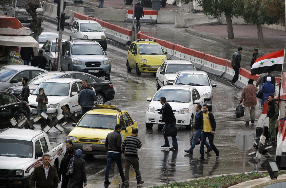 Syrians walk past cars in central Damascus on December 3, 2013 prior to a suicide attack in the Jebbeh district of the capital causing deaths and injuries, Syrian state television reported. (LOUAI BESHARA/AFP/Getty Images)