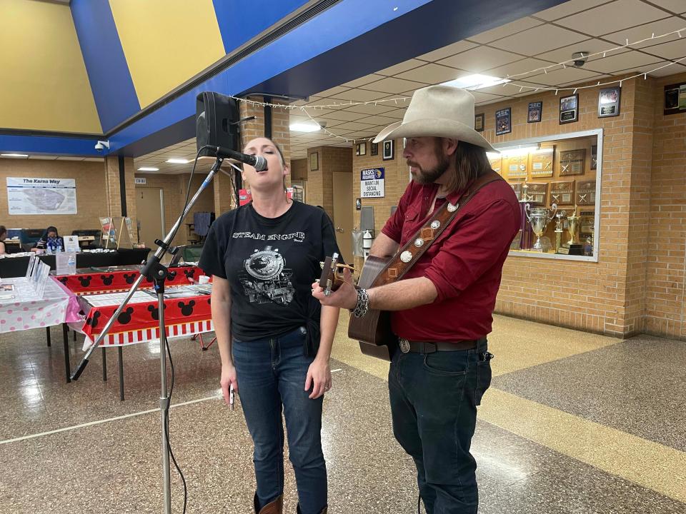 Pamela Cox and Eric Cox of the Steam Engine Band sing “Strawberry Wine” at the fourth annual Community Bazaar at Karns High School Saturday, April 30, 2022.