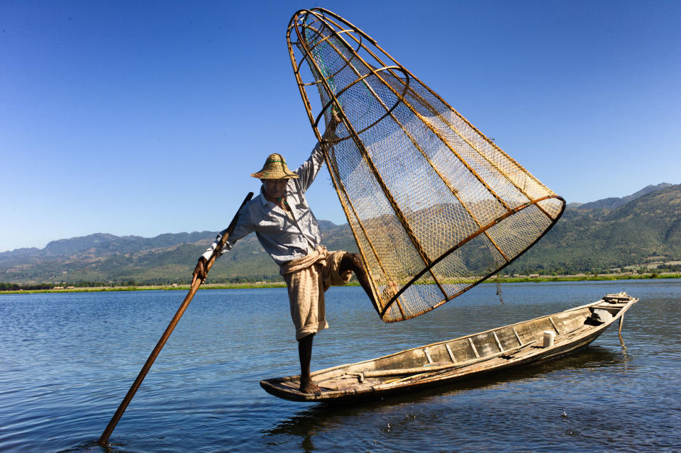 In this December 2012 photo a fisherman balances on his boat, net and oar in Inle Lake, Myanmar. (AP Photo/Richard Camp)