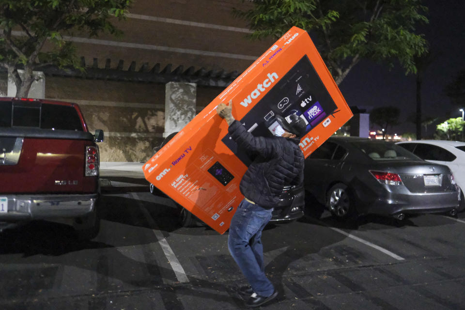 FILE - A Black Friday shopper wearing a face mask leaves a Walmart store with a TV in Pic Rivera Calif., Friday, Nov. 26, 2021. From appliance stores in the United States to food markets in Hungary and gas stations in Poland, rising consumer prices fueled by high energy costs and supply chain disruptions are putting a pinch on households and businesses worldwide. As economies recover from lockdowns caused by the COVID-19 pandemic, increased consumer demand has helped lead to rising inflation. (AP Photo/Ringo H.W. Chiu, File)