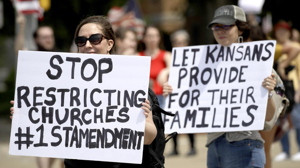 People hold signs at rally protesting coronavirus restrictions Friday, May 1, 2020, outside the Johnson County Courthouse in Olathe, Kan. (Charlie Riedel/AP)