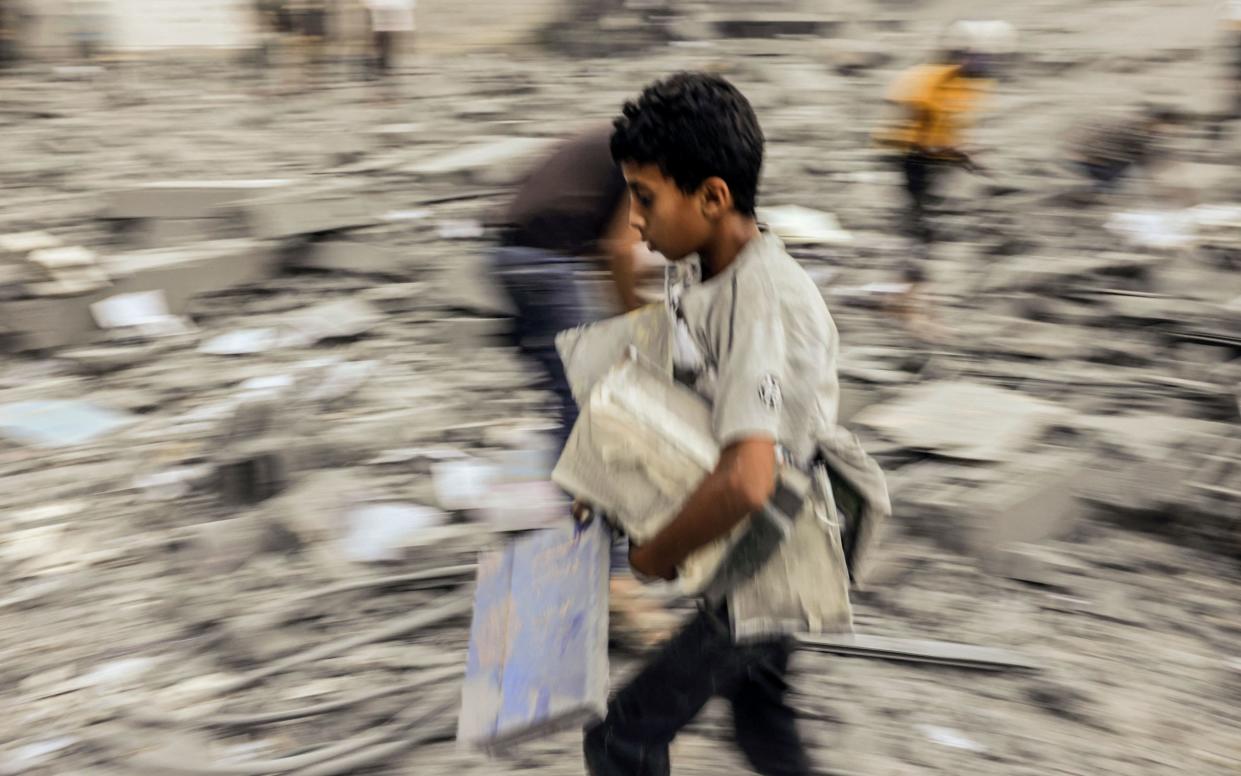 A child walks away with belongings salvaged from the rubble of a building hit in an Israeli strike on Rafah