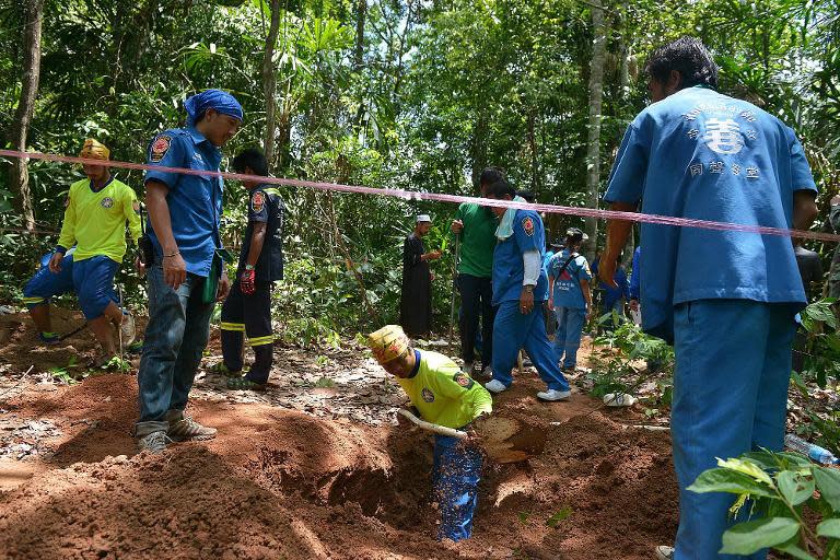 Thai rescue workers exhume human remains from a mass grave near the border town of Padang Besar, on May 6, 2015