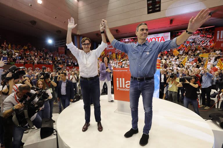 El primer ministro español, Pedro Sánchez, y el candidato del PSC, Salvador Illa, saludan desde el escenario durante la manifestación de clausura del Partido Socialista Catalán - PSC antes de las elecciones regionales en Cataluña, en Barcelona  (Photo by LLUIS GENE / AFP)