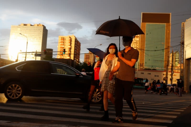 People wear protective masks as they cross a street following an outbreak of the coronavirus disease (COVID-19) in Beijing