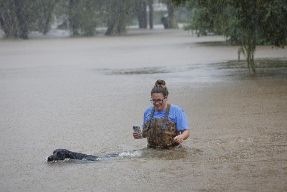 Adelle Puma and her dog "Ridge" makes their way from the submerged Mary Xing bridge over Marys Creek that leads into Clear Creek as Tropical Storm Beta rainfall trained over the area Tuesday, Sept. 22, 2020, in Friendswood, Texas. Puma and her husband just moved from Breaex Bridge, La., a moth ago and their home sits next to the bridge. (Steve Gonzales/Houston Chronicle via AP)