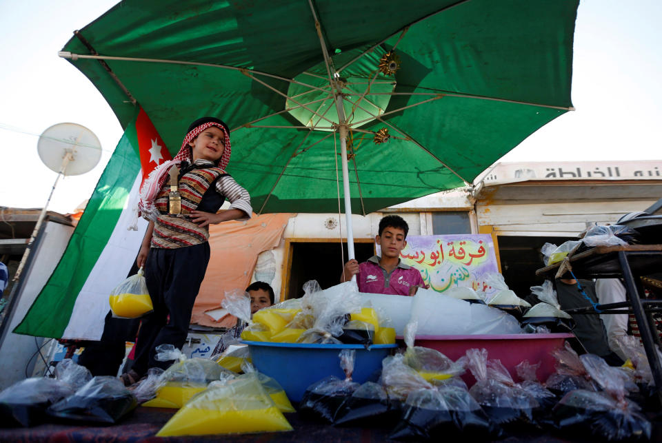 Members of the Syrian refugee folklore troupe Abu Rustom, sell traditional juices at the Al-Zaatari refugee camp on June 1.