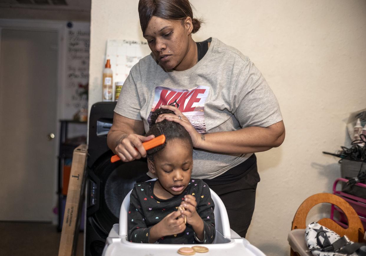 Ashley Joiner, 30, brushes her daughter's hair while Genayla Jerome, 2, eats a snack. The family with seven kids is rebuilding their lives after the death of a 3-year-old daughter.