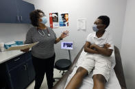 Jeremiah Young, 11, right, listens as Dr. Janice Bacon, a primary care physician, with Central Mississippi Health Services explains the necessity of receiving inoculations prior to attending school, Aug. 14, 2020, while at the Community Health Care Center on the Tougaloo College campus in Tougaloo, Miss. As a Black primary care physician, Bacon has created a safe space for her Black patients during the coronavirus pandemic. (AP Photo/Rogelio V. Solis)