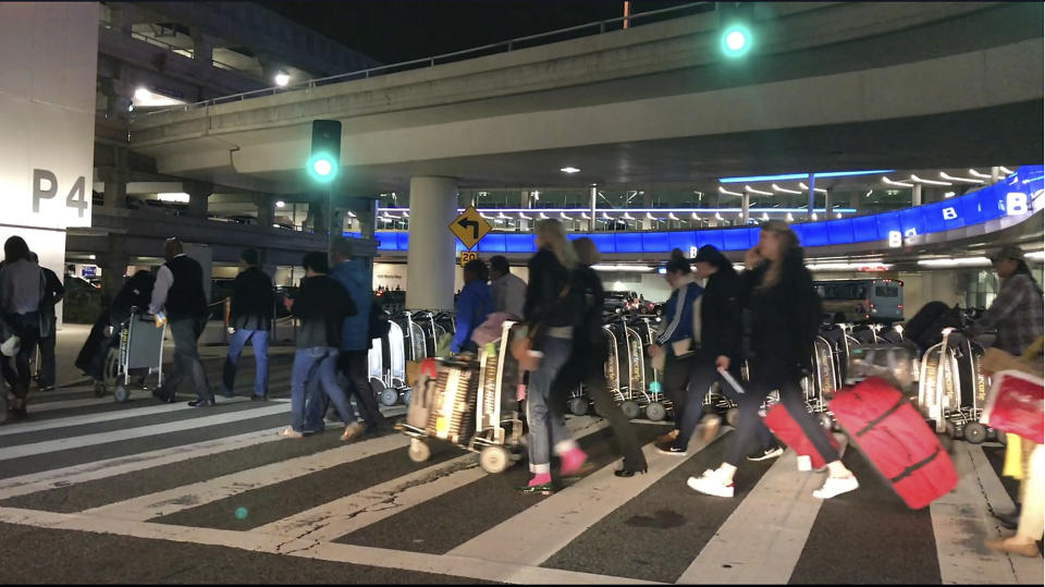 FILE - In this Wednesday, Dec. 21, 2016, file photo shows travelers leaving a terminal at Los Angeles International Airport. At the end of the month, travelers will not be able to hail a rideshare or taxi outside terminals at Los Angeles International Airport. LAX announced Friday, Oct. 4, 2019, that travelers will instead have to take shuttles or walk to a special location outside the central terminal area where they can be picked up.(AP Photo/Damian Dovarganes,File)