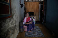 Asiyah poses for a photo in her rented home in Semarang, Central Java, Indonesia, Tuesday, Aug. 2, 2022. She and her family eventually abandoned their home and moved to this one in drier land, becoming climate migrants as many of their neighbors had before them. Their story illustrates how climate change can play a major factor in forcing people to migrate. (AP Photo/Dita Alangkara)