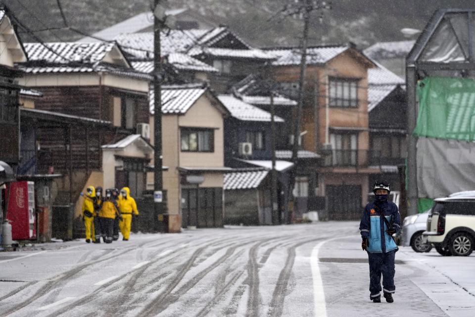 Police officers walk the snow-covered town in Wajima in the Noto peninsula facing the Sea of Japan, northwest of Tokyo, Sunday, Jan. 7, 2024. Monday's temblor decimated houses, twisted and scarred roads and scattered boats like toys in the waters, and prompted tsunami warnings. (AP Photo/Hiro Komae)