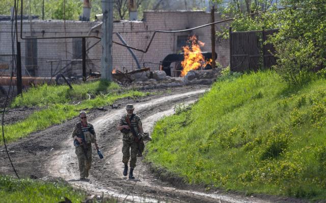 Ukrainian Army soldiers walk past a burning natural gas terminal on May 13, 2022 on the northern outskirts of Kharkiv - Photo by John Moore/Getty Images