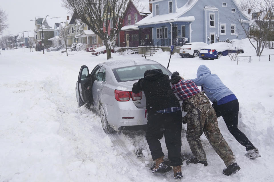 Neighbors help push a motorist stuck in the snow in Buffalo, N.Y., on Monday, Dec. 26, 2022. (Derek Gee/The Buffalo News via AP)