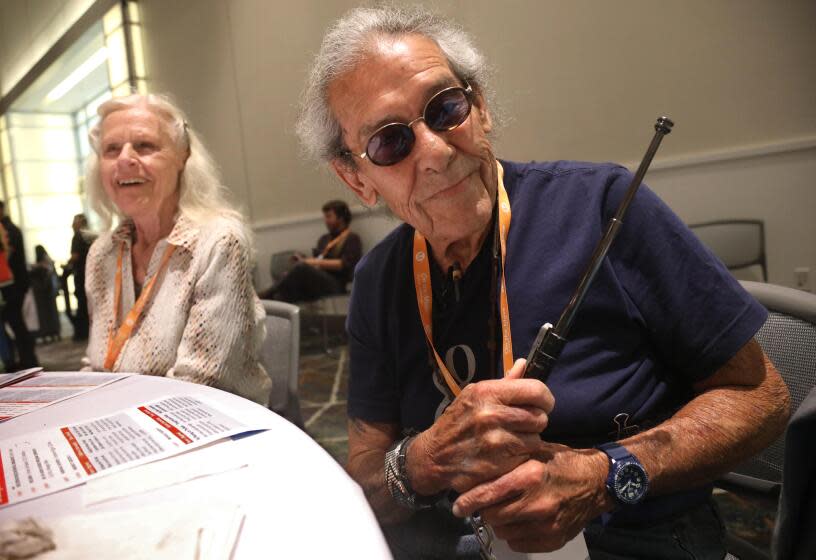 PASADENA, CA - MAY 7, 2024 - Vietnam vet Duane Garcia, 71, seated next to his friend Jan Wilander, 72, shows off the baton he carries for protection while riding Metro at the 8th Annual Older Adult Transportation Expo at the Pasadena Convention Center in Pasadena on May 7, 2024. "It's very risky every day," Garcia said about riding Metro. He also carries a pocket knife for protection. (Genaro Molina/Los Angeles Times)