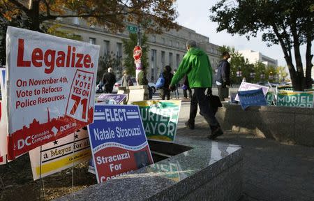 Pedestrians pass by a DC Cannabis Campaign sign in Washington in this November 4, 2014 file photograph. REUTERS/Gary Cameron/Files