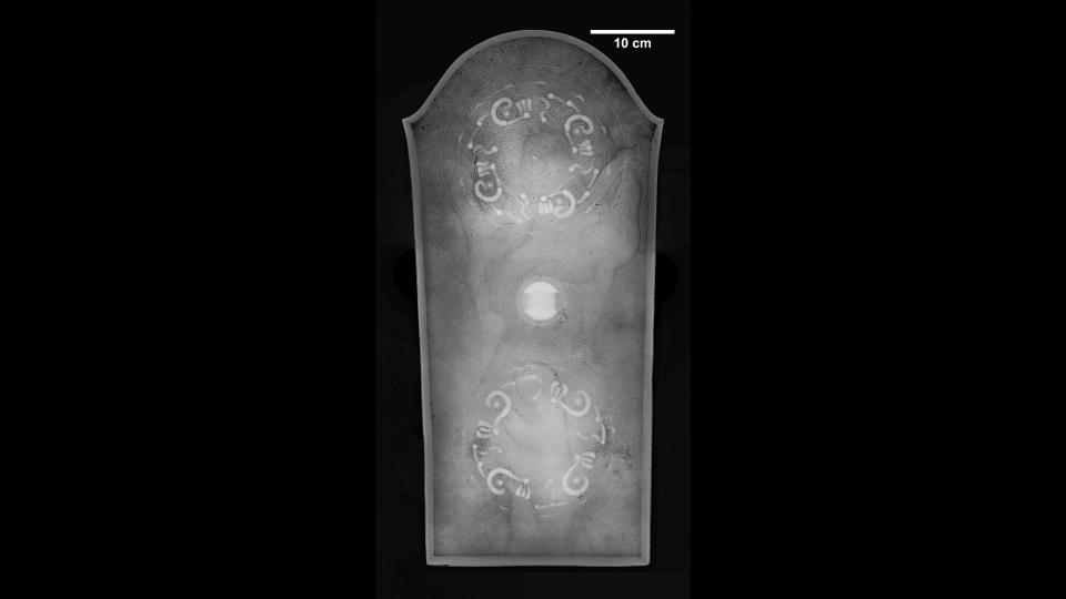 The bronze mirror in the shape of a shield is the largest artifact of this type ever found in Japan. X-ray photographs show where it was decorated by patterns in the metalwork.