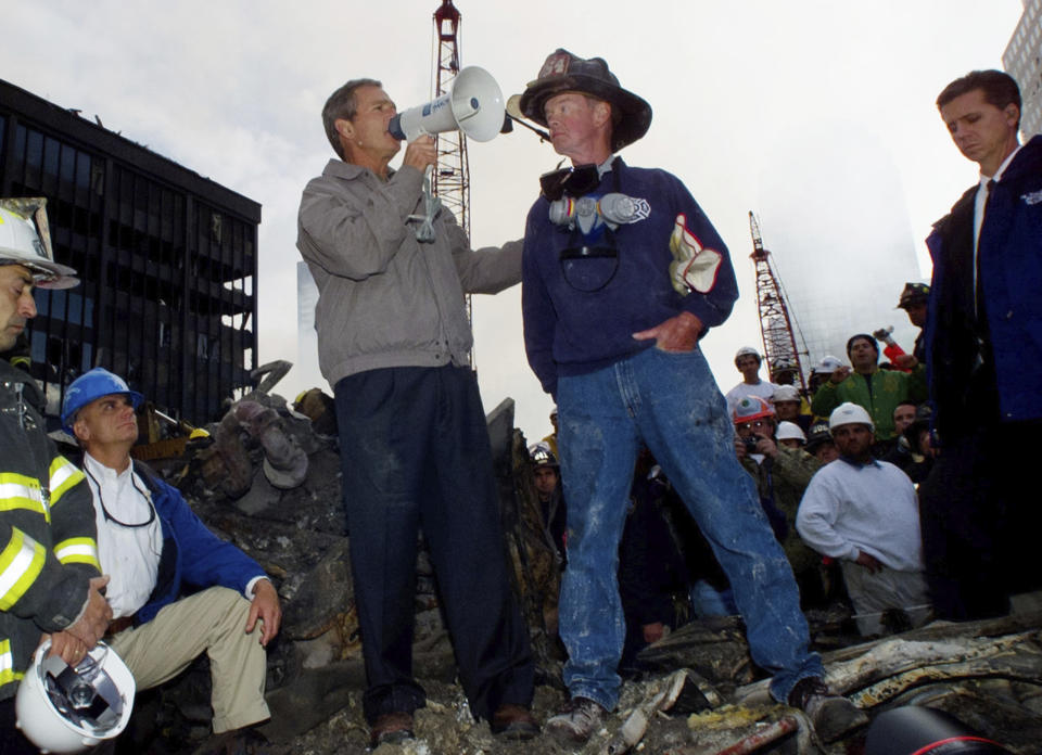 FILE - In this Sept. 14, 2001 file photo, as rescue efforts continue in the rubble of the World Trade Center in New York, President Bush stands with firefighter Bob Beckwith on a burnt fire truck in front of the World Trade Center during a tour of the devastation. In moments of crisis, American presidents have sought to summon words to match the moment in the hope that the power of oratory can bring order to chaos and despair.(AP Photo/Doug Mills, file)