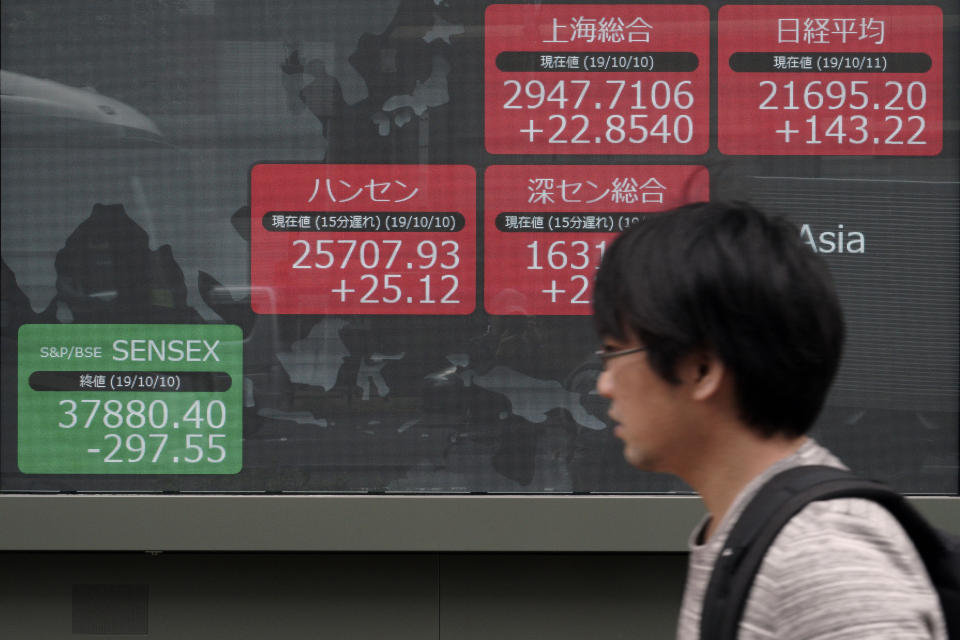 In this Oct. 11, 2019, photo, a man walks past an electronic stock board showing Japan's Nikkei 225 index and other Asian market index at a securities firm in Tokyo. Asian shares were mixed Monday, Oct. 21, amid uncertainties about Britain’s exit from the European Union and the ongoing trade conflict (AP Photo/Eugene Hoshiko)