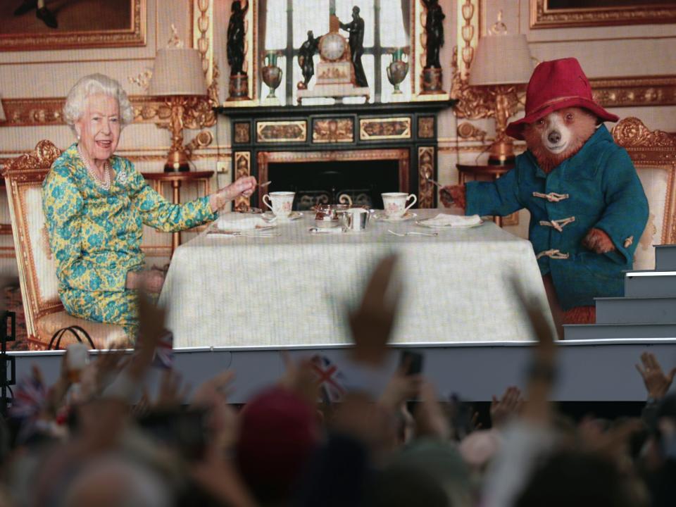 The crowd watching a film of Queen Elizabeth II having tea with Paddington Bear on a big screen during the Platinum Party at Buckingham Palace.