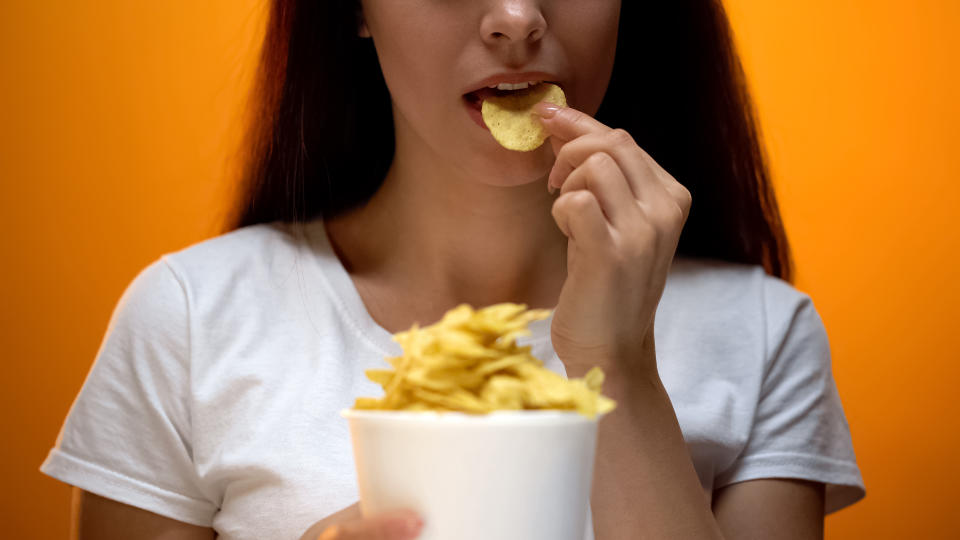 Mujer comiendo patatas fritas.