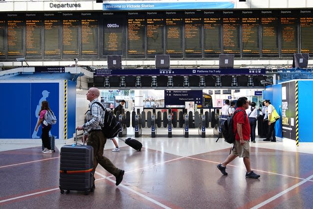 Passengers walk in a station hall, above the departure board