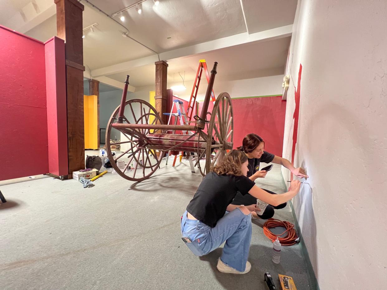 COS Gallery Exhibition class students Grayce Martin, foreground and Denisse Mederos, background, touch up with white paint at CACHE, the Center for Art, Culture and History-Exeter.