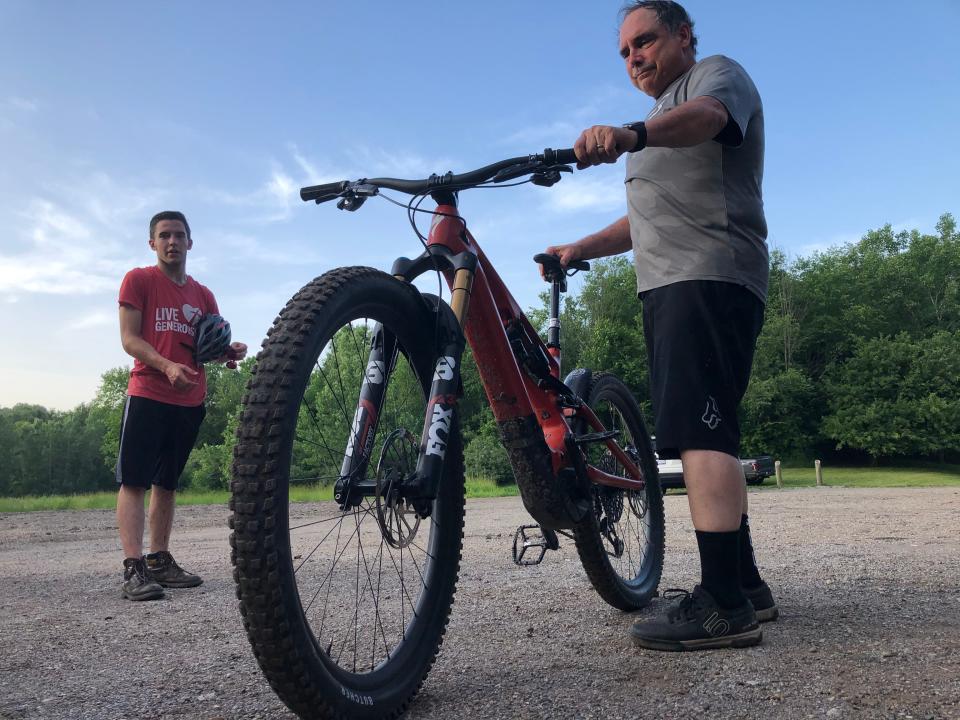 Pierre Crevier, who is overcoming cancer, holds his e-assist mountain bike after a group ride on the mountain bike trail at Andrews University in Berrien Springs.