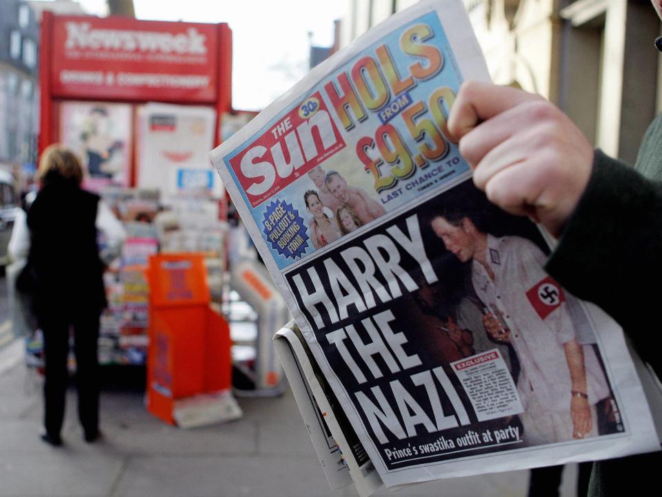 A man reads The Sun newspaper in London 13 January, 2005, with a headline about Prince Harry wearing a Nazi uniform at a costume party.