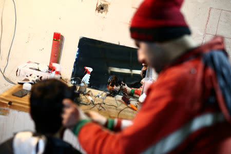 A migrant cuts another's hair in a migrant camp in Bihac, Bosnia and Herzegovina, December 14, 2018. Picture taken December 14, 2018. REUTERS/Antonio Bronic