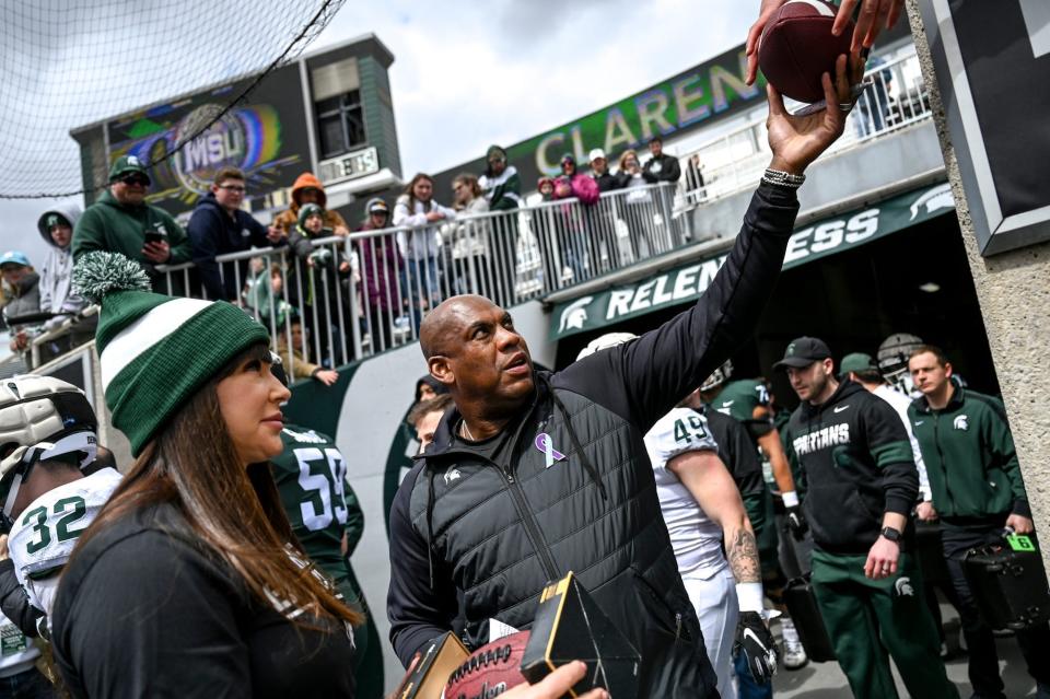 Michigan State head coach Mel Tucker, right, hands back a signed football for fans on Saturday, April 16, 2022, during the spring game at Spartan Stadium in East Lansing. At left is honorary captain Brenda Tracy, sexual violence prevention educator.