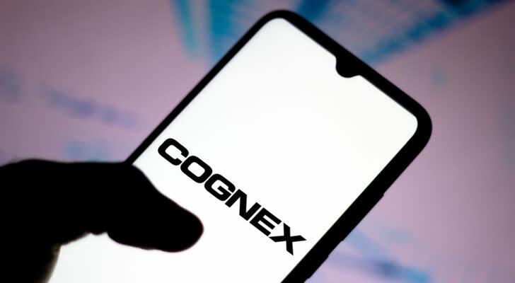 Cognex (CGNX) logo displayed on smartphone with pink and blue background behind, symbolizing CGNX stock