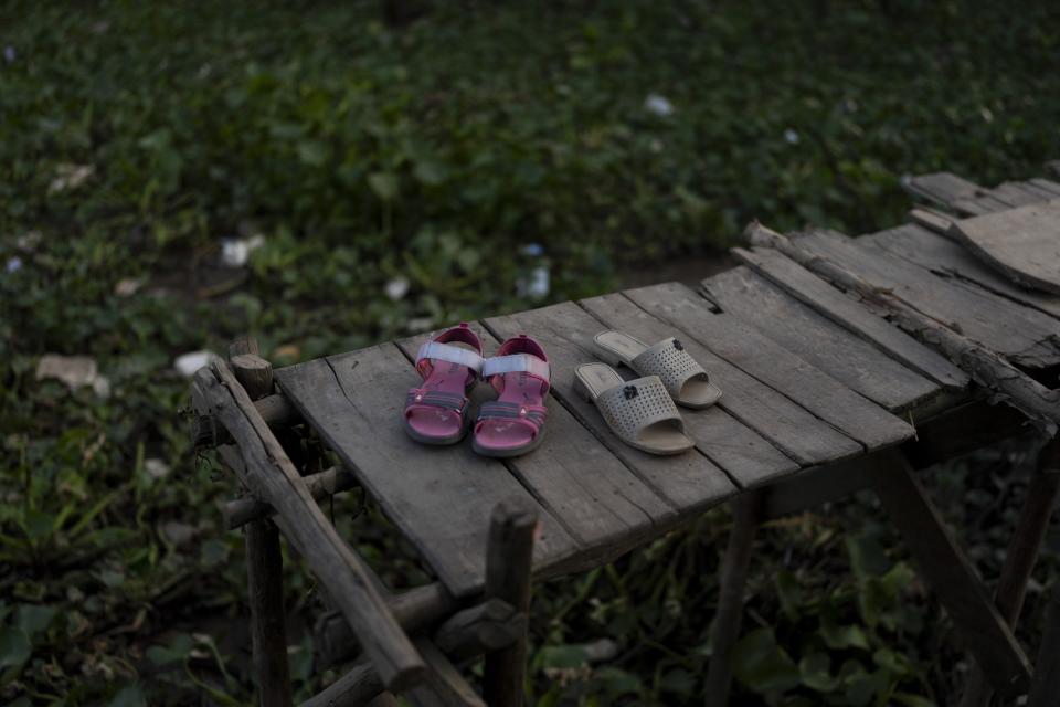Do Bao Tran's pink sandals are placed next to her grandmother's on a weathered bridge that connects the land to their shanty houseboat in Can Tho, Vietnam, Wednesday, Jan. 17, 2024. After their mother left to pursue better financial opportunities in Ho Chi Minh City, Tran and her twin brother remained in the care of their grandmother, who supports the family by selling steamed buns at a floating market. (AP Photo/Jae C. Hong)